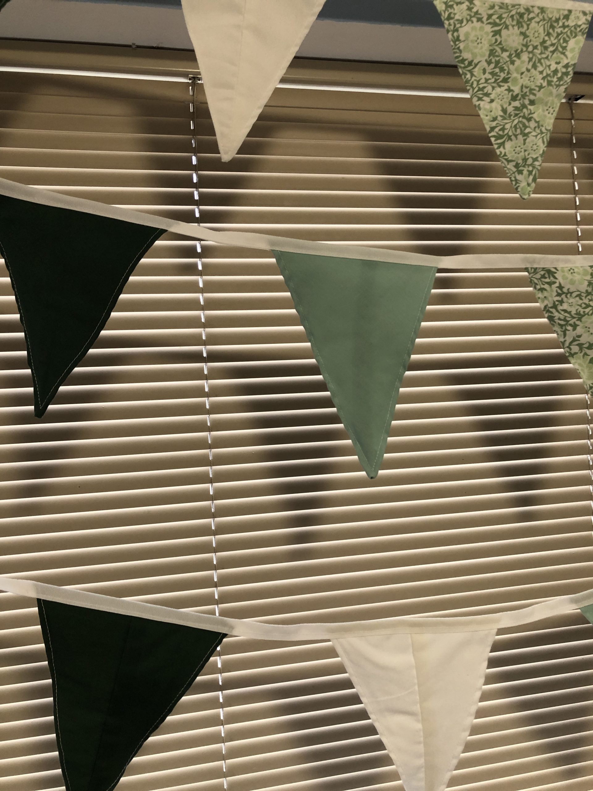 Fabric bunting made from waste fabric in greens and white.