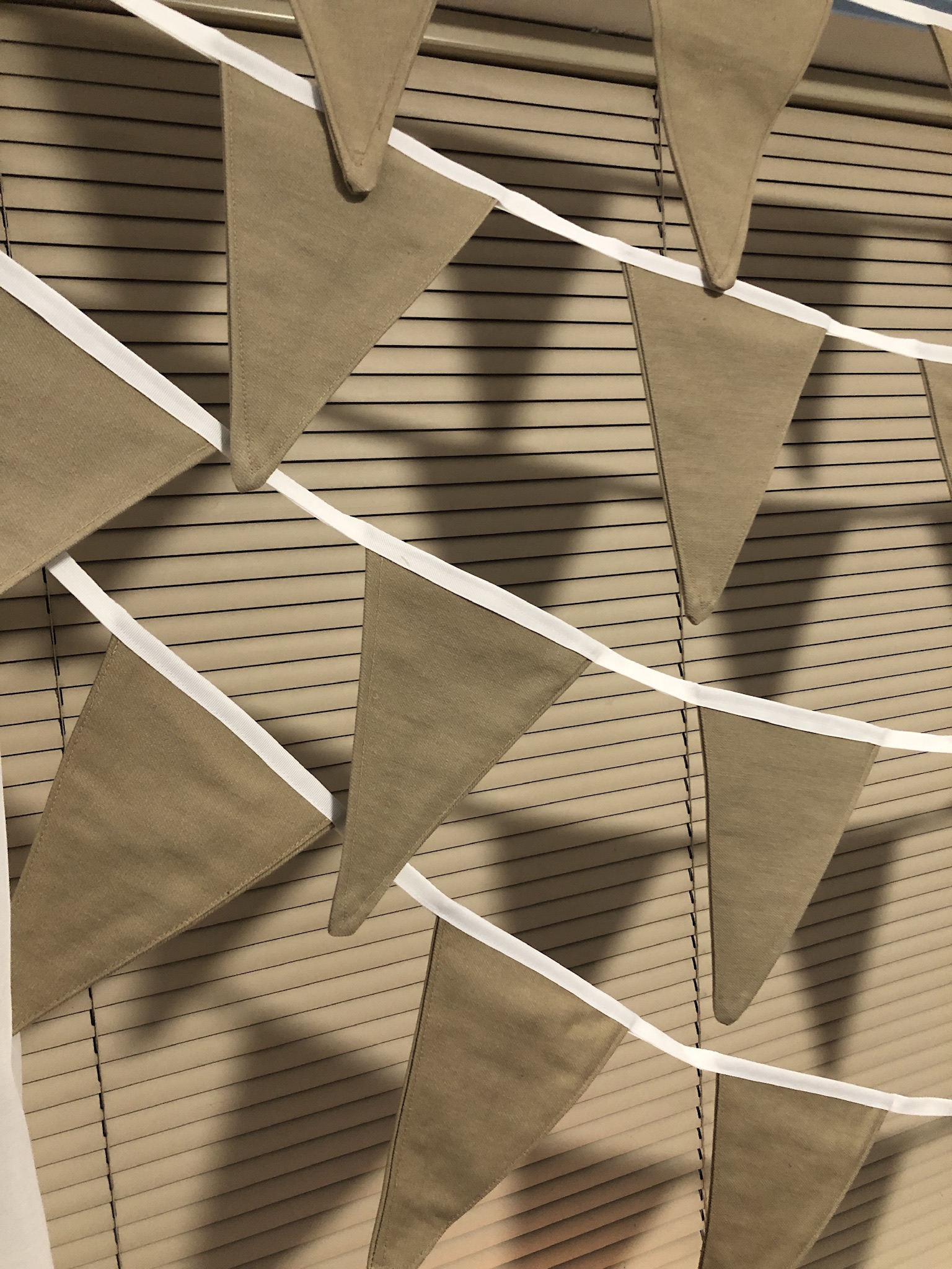 100% cotton bunting in beige hanging in a window. 100% cotton bunting in beige hanging in a window.