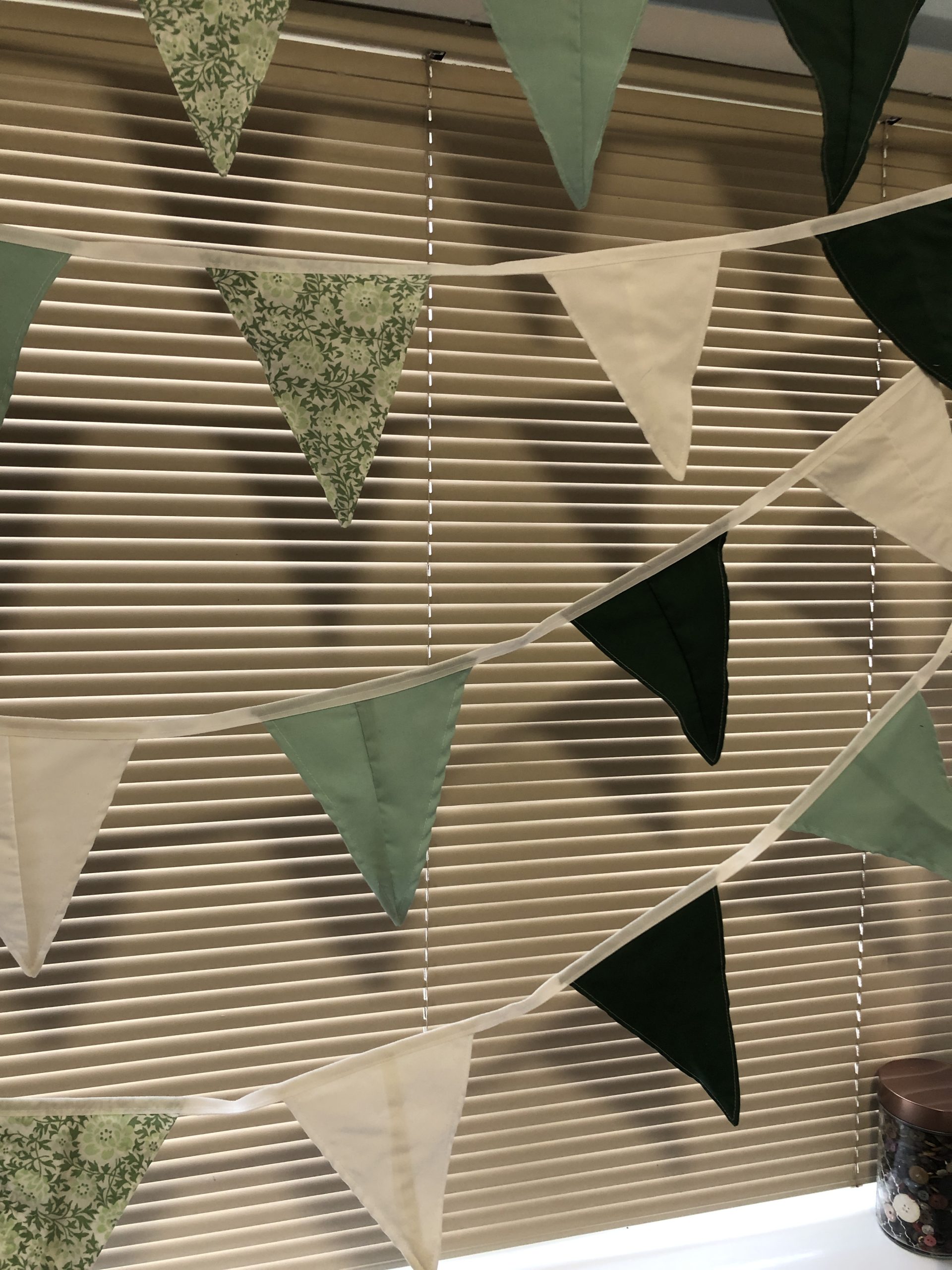 Fabric bunting made from waste fabrics. Flags are in shades of green and white with some flora and fauna patterning. Fabric bunting made from waste fabrics. Flags are in shades of green and white with some flora and fauna patterning.
