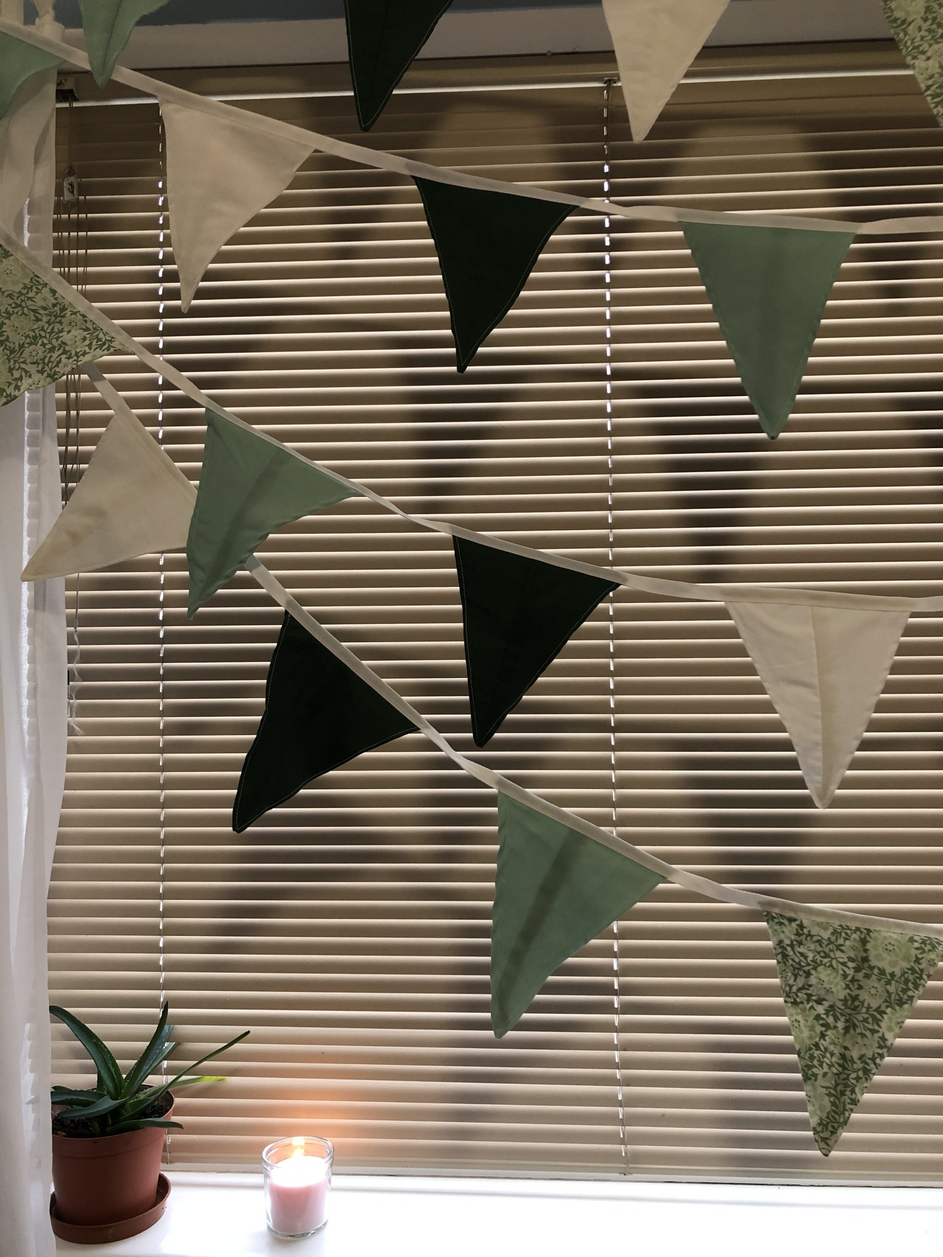 Bunting made from repurposed fabric in greens and white. Flora and fauna patterns. Bunting in greens and white with patterns of flora and fauna.